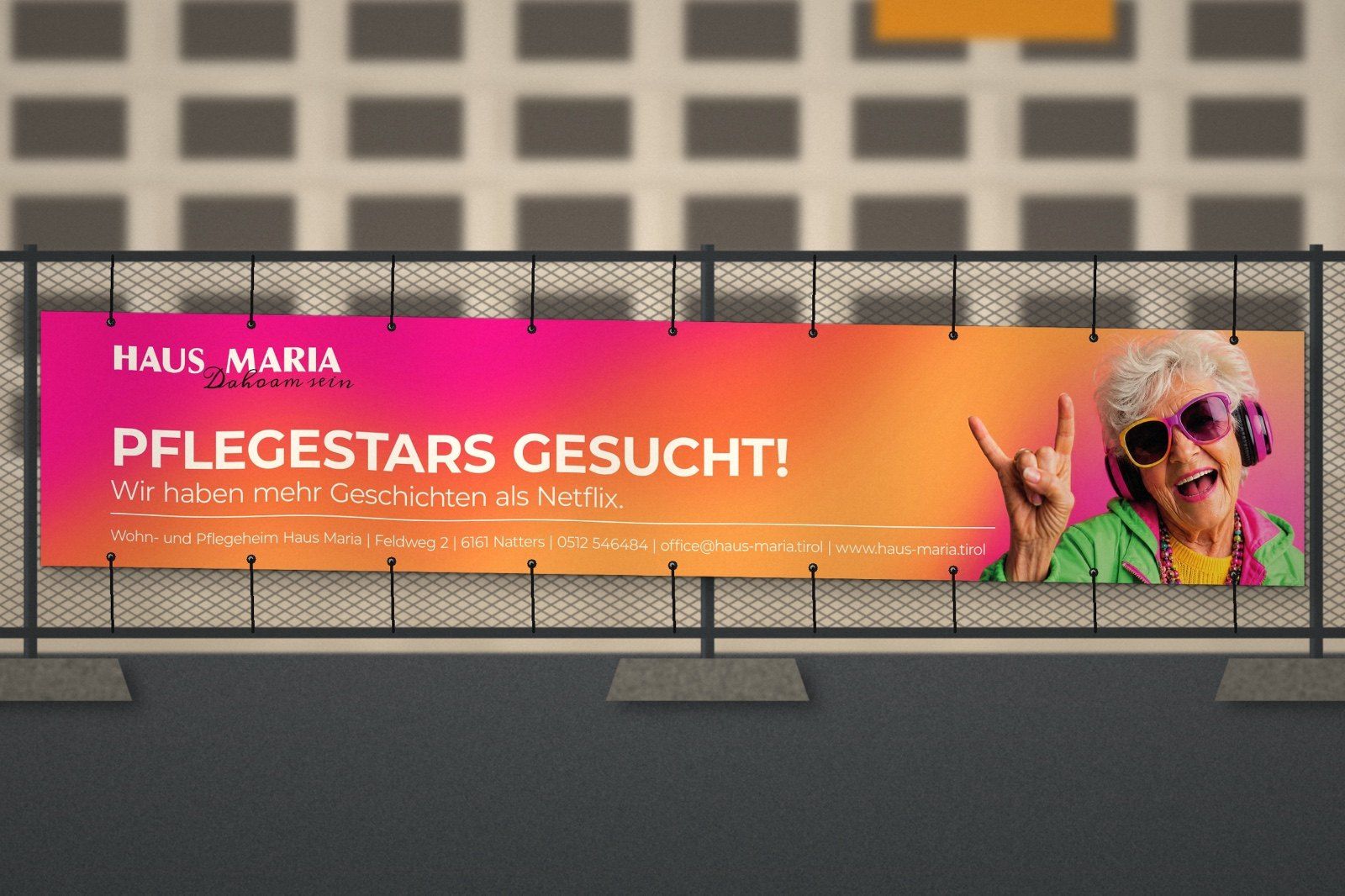 Banner „Pflegestars gesucht! Wir haben mehr Geschichten als Netflix.“ an einem Zaun, daneben eine ältere Dame mit Sonnenbrille und Kopfhörern